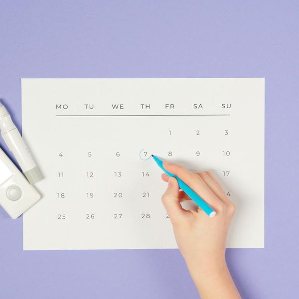 Calendar with a marked daily schedule next to a glass of water.